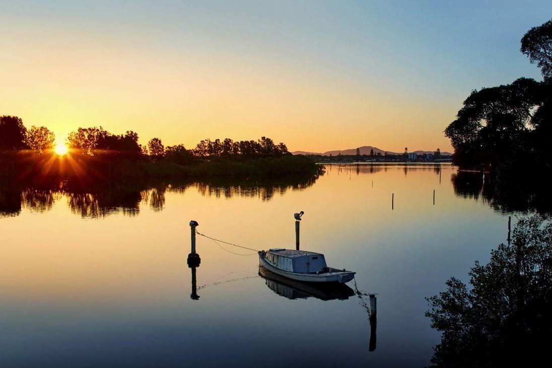 A small boat on Wallis Lake at sunset
